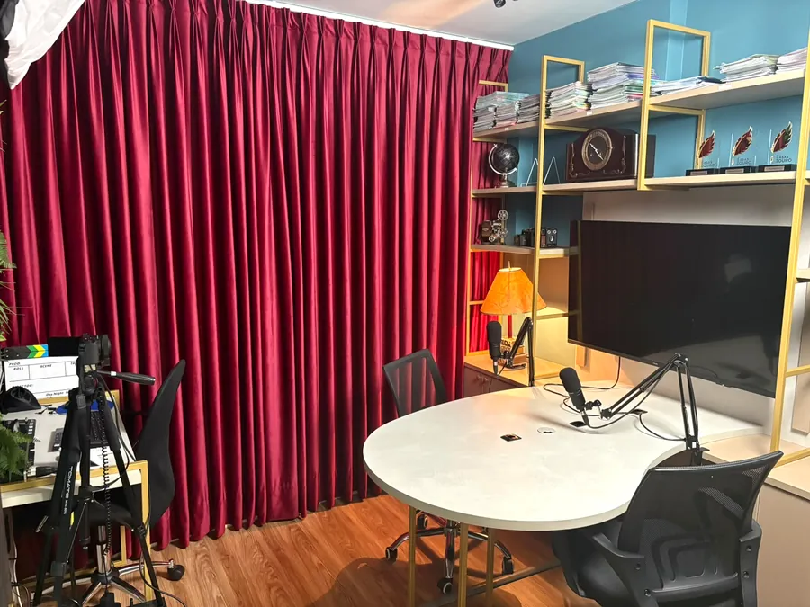 Estúdio de podcast com mesa, microfones e cortina de veludo