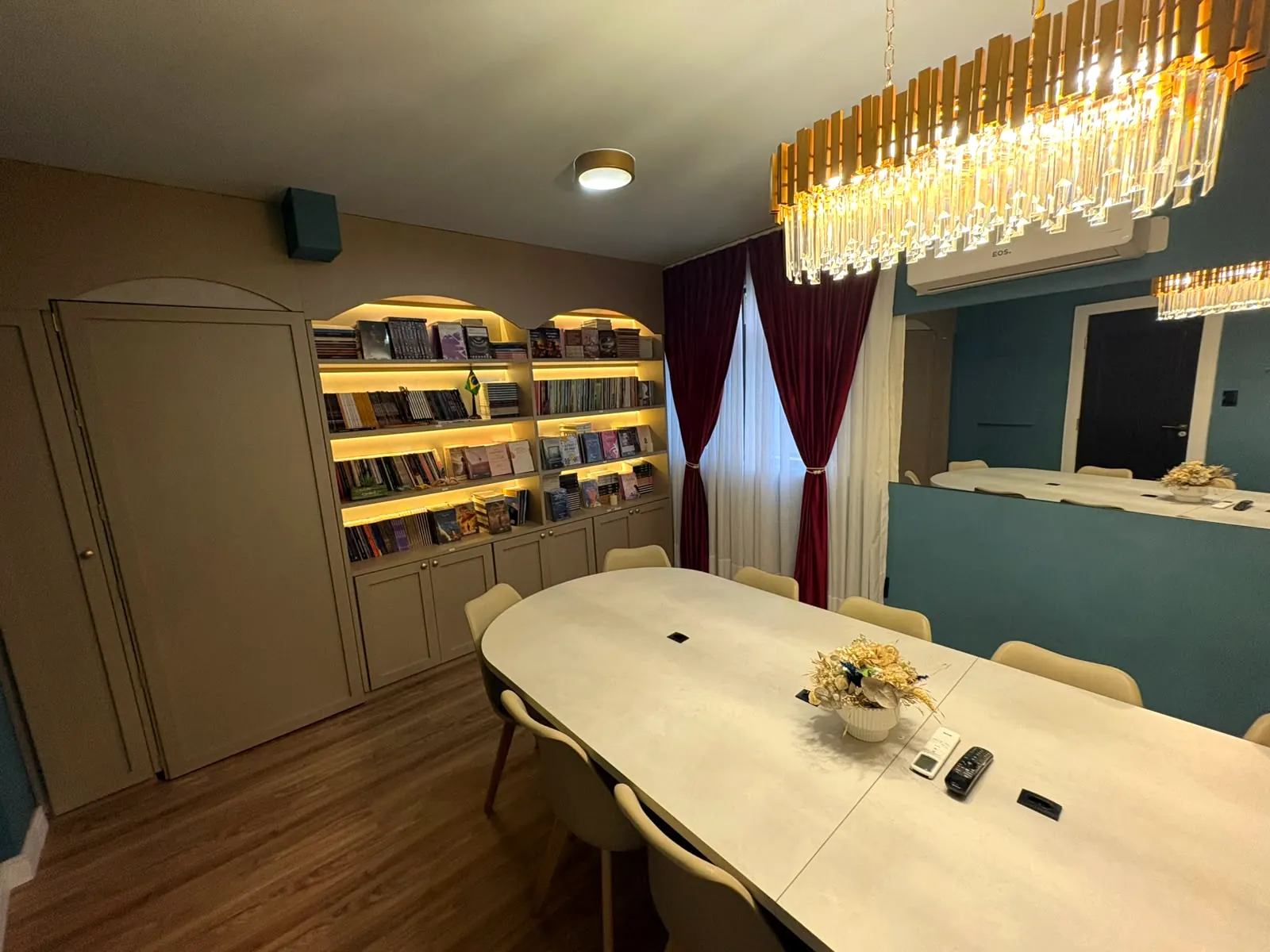 Sala de reunião com mesa para 12 pessoas e estantes iluminadas