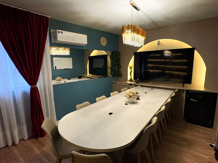 Sala de reunião com cortinas de veludo bordô, lustre de cristal dourado e nicho em arco iluminado