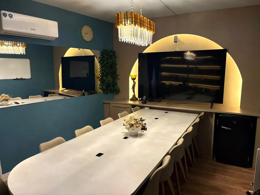 Sala de reunião com mesa para 12 pessoas e telão no nicho em arco