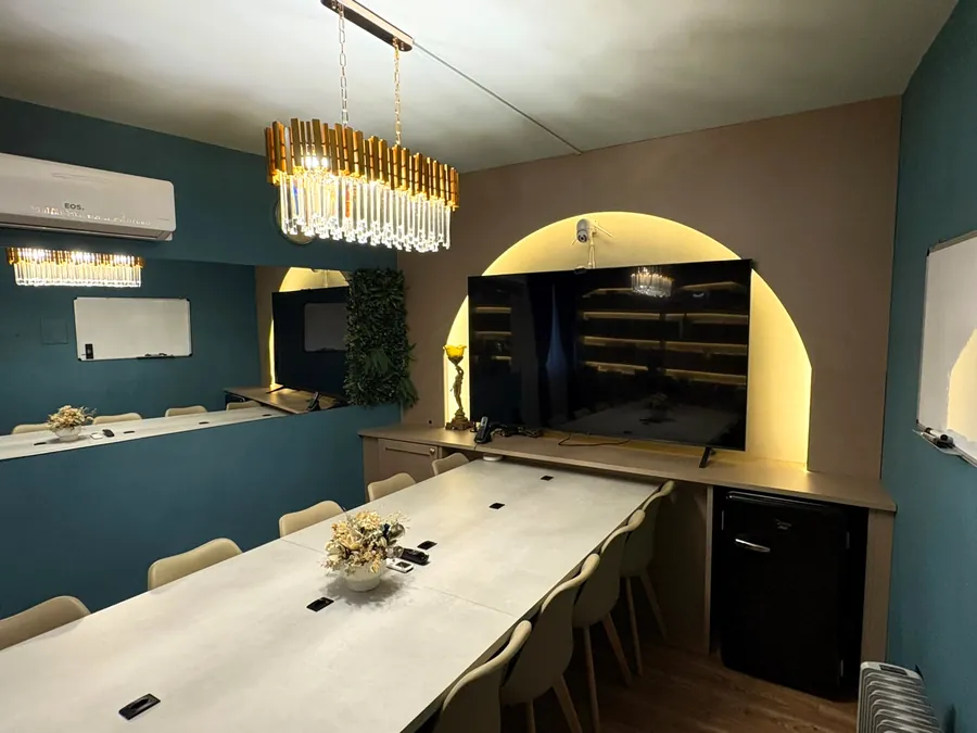 Sala de reunião com mesa longa, telão e lustre